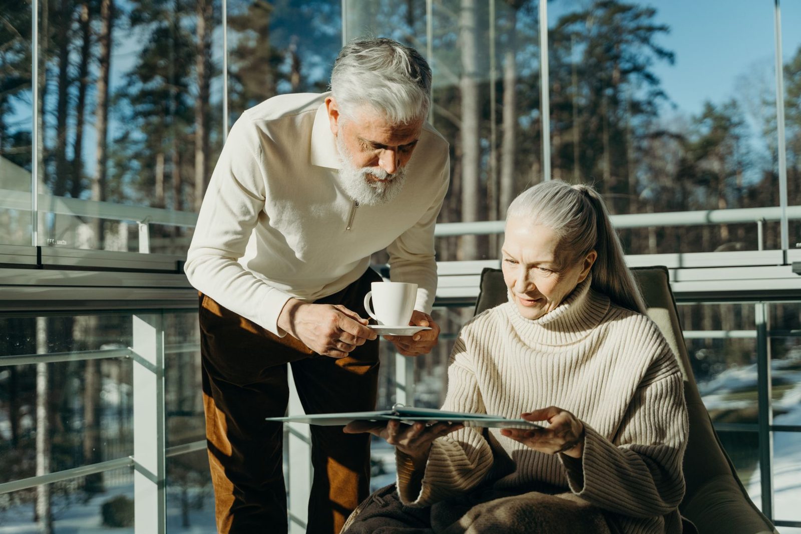 Older couple sharing tea in a bright glass-walled room