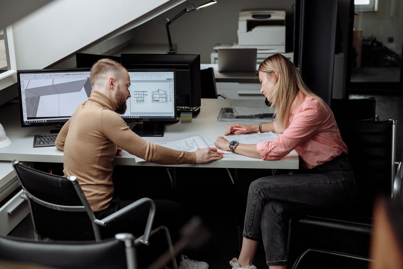 Couple reviewing building plans with a designer
